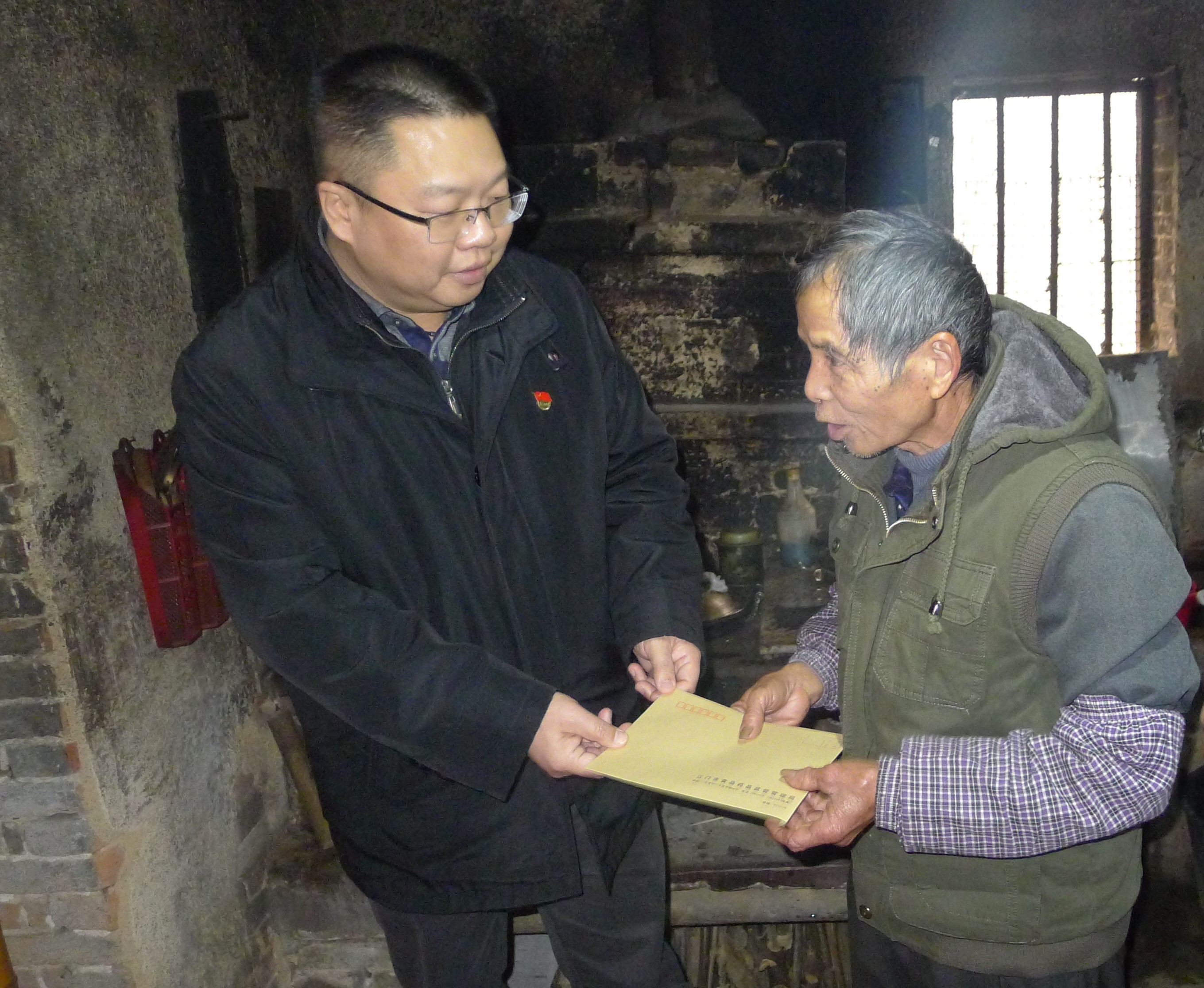 圖為：江門(mén)市食品藥品監(jiān)督管理局黨組成員、紀(jì)檢組長(zhǎng)蔣業(yè)洲向黃村村委會(huì)吳達(dá)文送上春節(jié)慰問(wèn).jpg